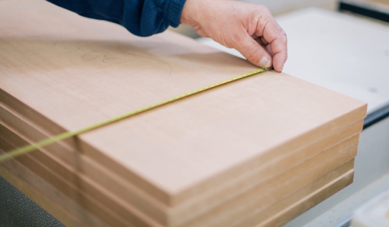 Das Foto zeigt wie eine Person Holt mit einem Maßband abmisst