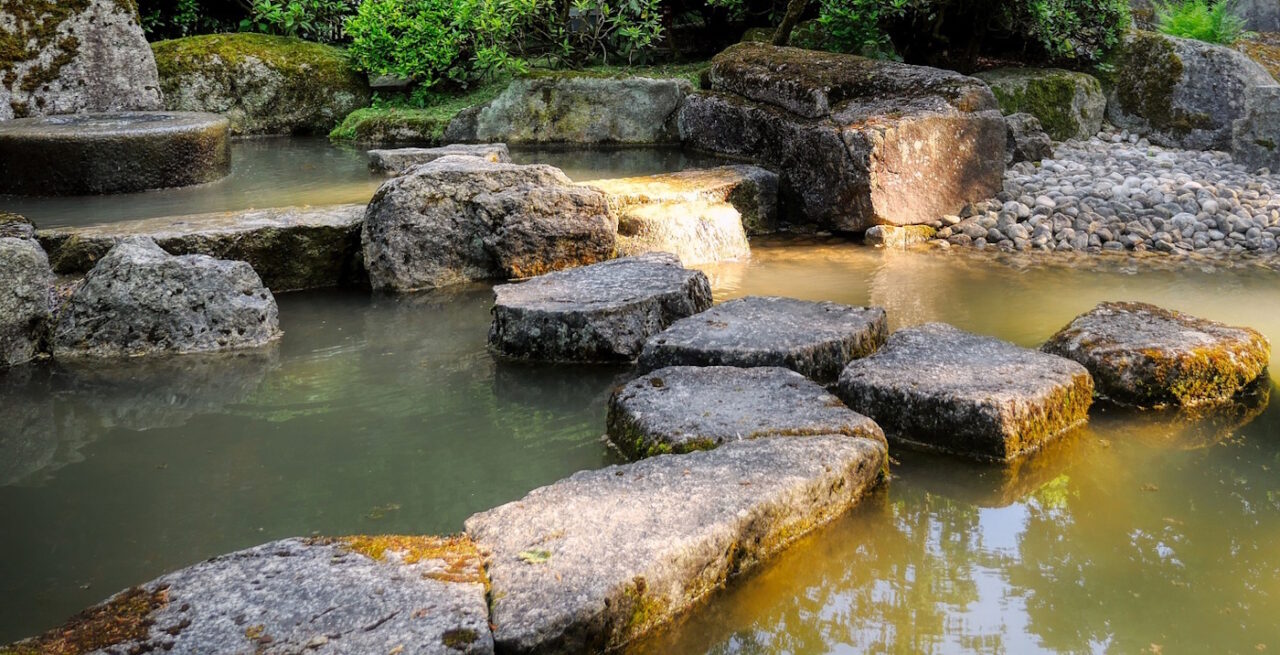 Das Foto zeigt Begrenzungen aus Stein in einem Teich